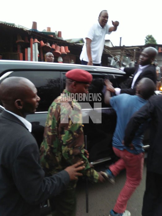 Dennis Murimi Wachiri (in blue shirt), a sweets hawker along Jogoo Road, is held back by President Uhuru Kenyatta's security detail. PHOTO | EMMA NZIOKA