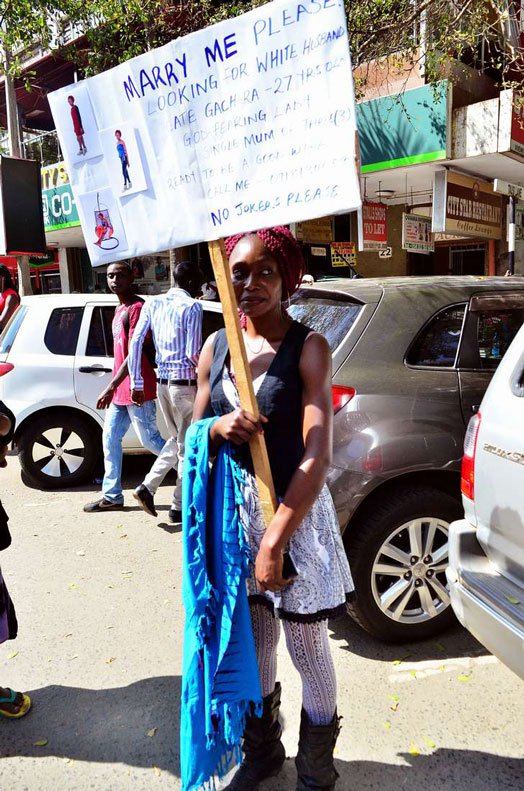 Cate Gachara, 27, a single mother of three children pictured along Kimathi Street, Nairobi with her 'Marry Me Please' placard. PHOTO | FRANCIS NDERITU